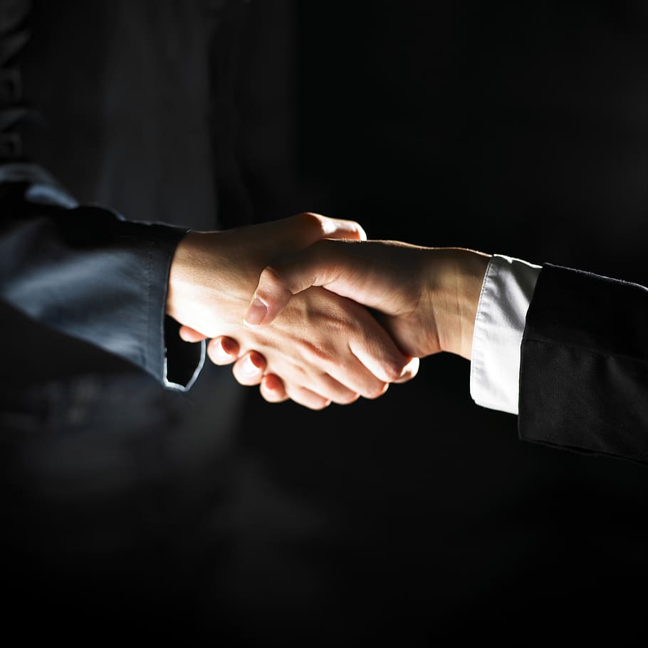 Two business people shaking hands on a black background.